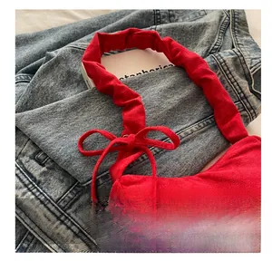 Gros plan d'un sac en daim rouge avec bandoulière froncée et détail de nœud