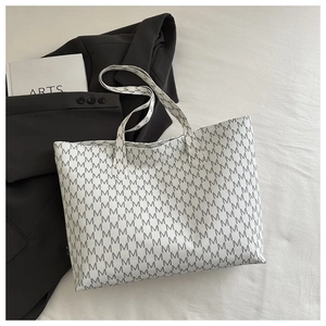 Flat lay of white tote bag with gray M letter patterns, black blazer and arts book