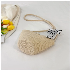 Detailed view of woven straw bucket bag with pearl clasp and polka dot bow accent