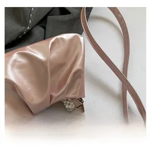 Detail of pearlescent pink pleated handbag with pearl handle and metallic texture
