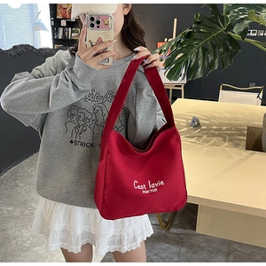 Detail of red canvas tote bag featuring white C'est lavie PAN'TOR embroidery text
