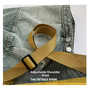 Detail of adjustable woven yellow strap on blue denim saddle bag with silver buckles