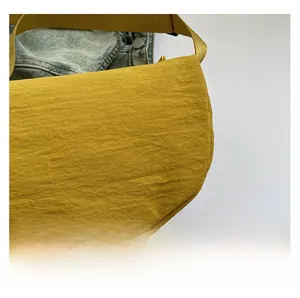 Macro detail of ginger yellow crossbody bag showing crinkled nylon fabric texture