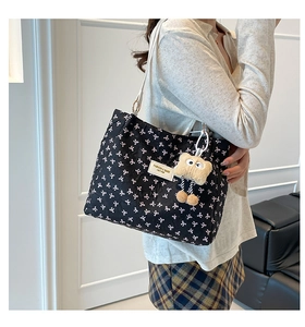 Sac fourre-tout matelassé avec nœuds roses et pendentif peluche porté à l'épaule