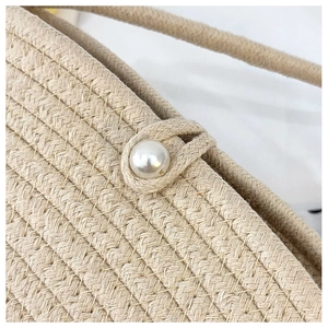 Close-up of beige woven straw texture with a pearl button closure and braided strap