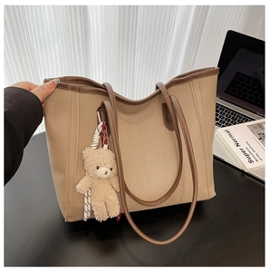 Detailed view of beige large tote bag with litchi texture and cute bear pendant charm