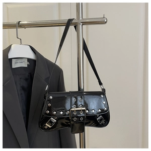 Close-up of black patent leather shoulder bag with punk silver metal eyelets and rivets