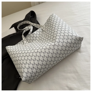 Detail of large tote bag showing black M-letter monogram print on white PU leather