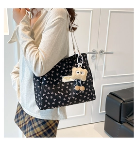 Gros plan d'un sac cabas noir matelassé avec motifs nœuds roses et pendentif en peluche