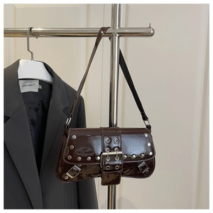 Detail of dark brown patent leather shoulder bag featuring silver rivets and metal eyelets