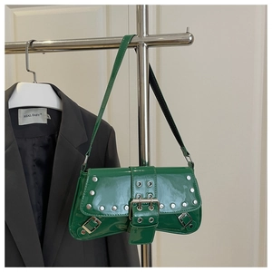 Close-up of shiny green patent leather shoulder bag with silver studs and metal buckle