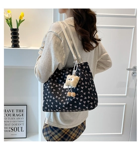 Détail du sac cabas noir avec motifs de nœuds roses, lanières blanches et bijou