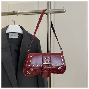 Detail of red patent leather shoulder bag with silver studs and metal belt buckles