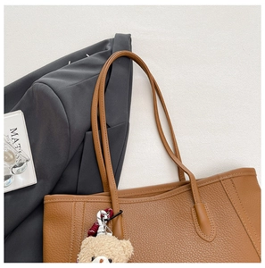 Détail du sac cabas en cuir marron avec motif litchi et un pendentif ours