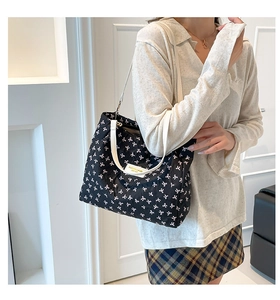 Détail d'un sac à bandoulière matelassé noir avec motifs nœuds blancs et logo