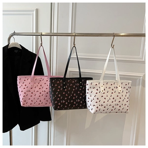 Three cherry print tote bags in pink, black, and white colors with gold metal rivets