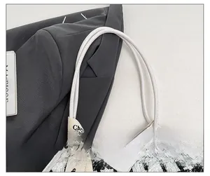 Détail des anses en cuir blanc et texture pied-de-poule d'un grand sac cabas
