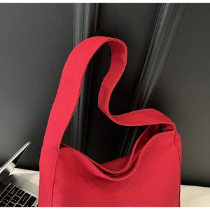 Detail view of red canvas tote bag showing thick texture, wide strap, and zipper closure