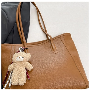 Vue détaillée du sac cabas en cuir grainé caramel avec breloque ours en peluche