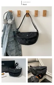 Detail of black nylon crescent crossbody bag featuring adjustable strap and logo