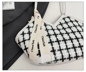 Détail du sac cabas en tweed à carreaux noir et blanc avec ruban et écusson de mode