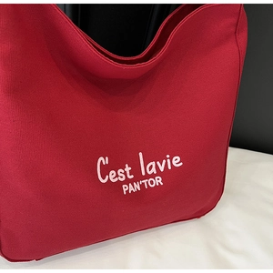 Close-up of red canvas tote bag showing white C'est la vie text and premium fabric texture