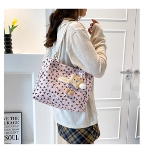 Détail d'un sac cabas rose avec imprimés nœuds noirs et porte-clés en peluche