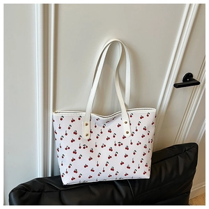 Close-up of the cherry print pattern and leather texture on the cream tote bag
