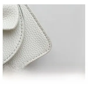 Nahaufnahme von weißem Narbenleder und feiner Naht an einer luxuriösen Mini-Handtasche