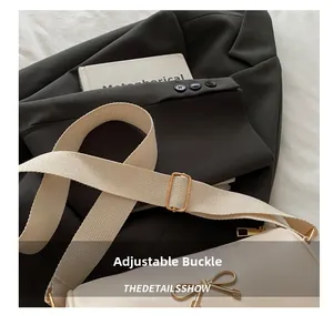 Detail of adjustable gold metal buckle on beige wide shoulder strap for PU leather bag