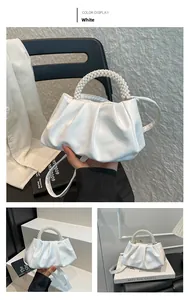 Detail of white pleated cloud handbag featuring elegant pearl bead handle and leather strap