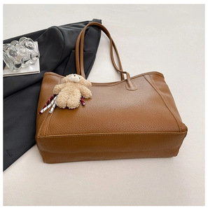 Détail d'un sac cabas en cuir marron grainé litchi avec pendentif ours en peluche