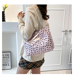Détail d'un sac cabas rose avec imprimés nœuds noirs et fine bandoulière blanche
