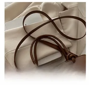Detail of adjustable shoulder strap and knotted handle on a brown patchwork crossbody bag