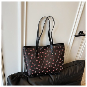 Detail of cherry print tote bag featuring black leather and golden rivet hardware