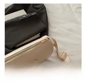 Detail of smooth gold zipper and metallic bow charm on a cream beige small square bag