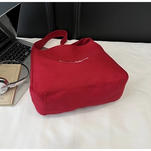 Detail of red canvas tote bag with white C'est la vie print in a work scene