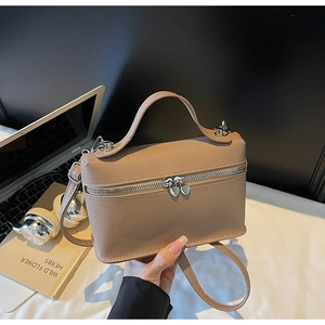 Close-up of light brown lychee grain leather vanity bag with silver heart zipper detail