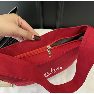 Detailed macro view of the smooth metal zipper and gray lining of the red canvas tote bag