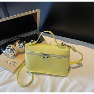 Detail of yellow pebbled leather handbag with heart-shaped zipper charms on a desk