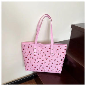 Close-up of pink tote bag with cherry print, golden rivets and PU leather texture