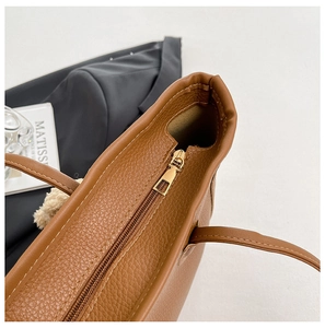 Detailed macro view of the zipper closure and pebble grain leather on brown tote bag