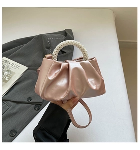 Detail of pink satin cloud bag featuring pleated design and round pearl handle