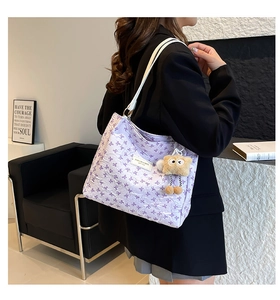 Détail d'un sac cabas violet à motifs de nœuds avec breloque ours et texture textile