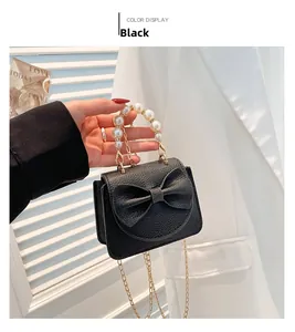 Detailansicht der schwarzen Lederhandtasche mit Schleife und Perlenhandgriff