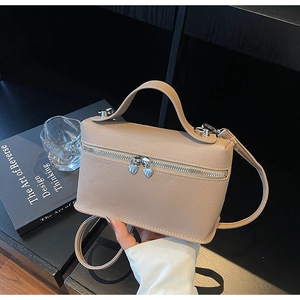 Detail of beige lychee grain handbag featuring silver heart-shaped zippers and leather strap