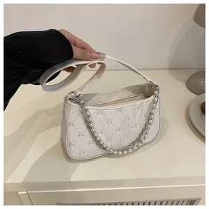 Détail macro du sac à bandoulière matelassé blanc avec chaîne en perles et métal argenté
