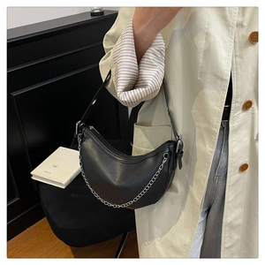 Detail of black pebbled leather crescent bag featuring silver chain and adjustable strap