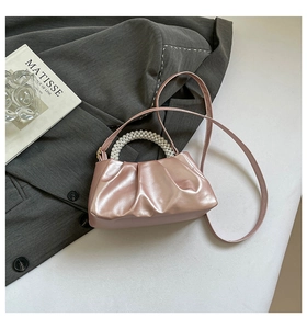 Detail of pink ruched cloud bag featuring white pearl handle and metal sheen texture