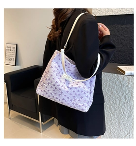 Détail du sac cabas lilas avec motifs de nœuds 3D et bandoulière blanche en intérieur